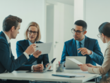Business professionals in modern office negotiating SaaS contract with documents and laptops