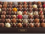 Assorted premium truffle chocolates in an elegant box on white background
