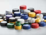 Variety of plastic closure bottle caps including screw caps, flip-top caps, and tamper-evident rings on a clean white background