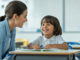 Elementary school child with autism receiving personalized ABA therapy support from a therapist in a bright classroom.