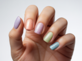 Close-up of glossy gel polish manicure nails with pastel colors and subtle glitter accents on clean white background