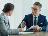 Photo of a businessperson meeting an insurance agent discussing commercial insurance options in a professional setting with neutral background